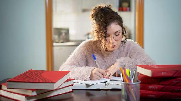 Studentin bereitet sich am Schreibtisch auf eine Prüfung vor