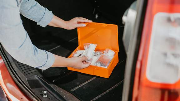 Junge Frau mit Erste-Hilfe-Kit-Box im Auto